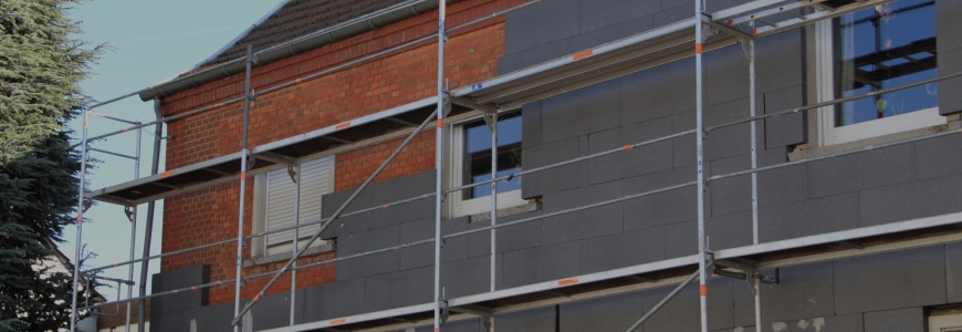 Woning met steigers waar gevelisolatie wordt aangebracht met grijze isolatieplaten aan de buitenmuur.